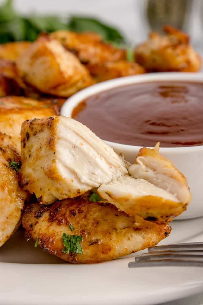 cutting into chicken chunks with a bbq dipping sauce 