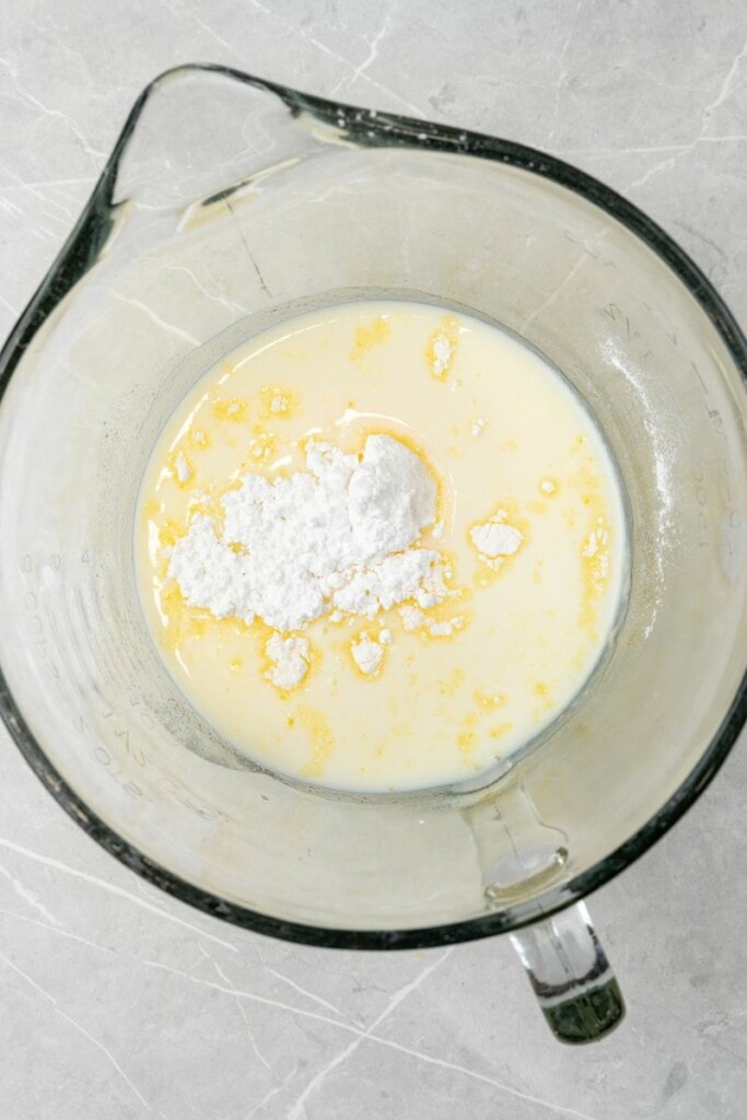 adding pudding mix with sugar and milk in a bowl 