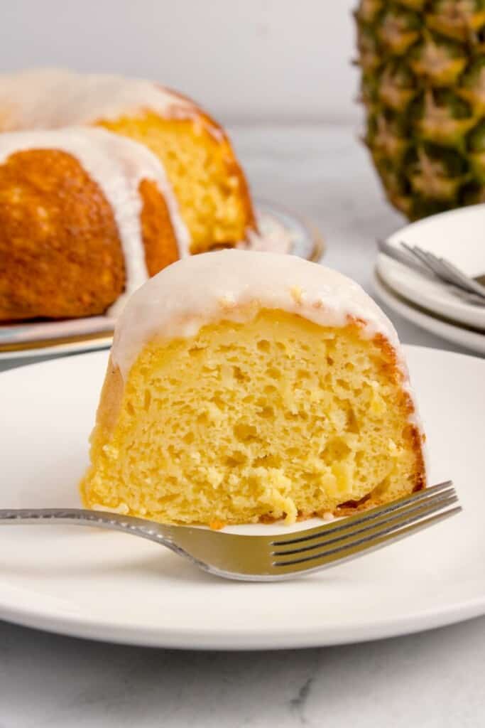 slicing pineapple bundt cake on a plate 