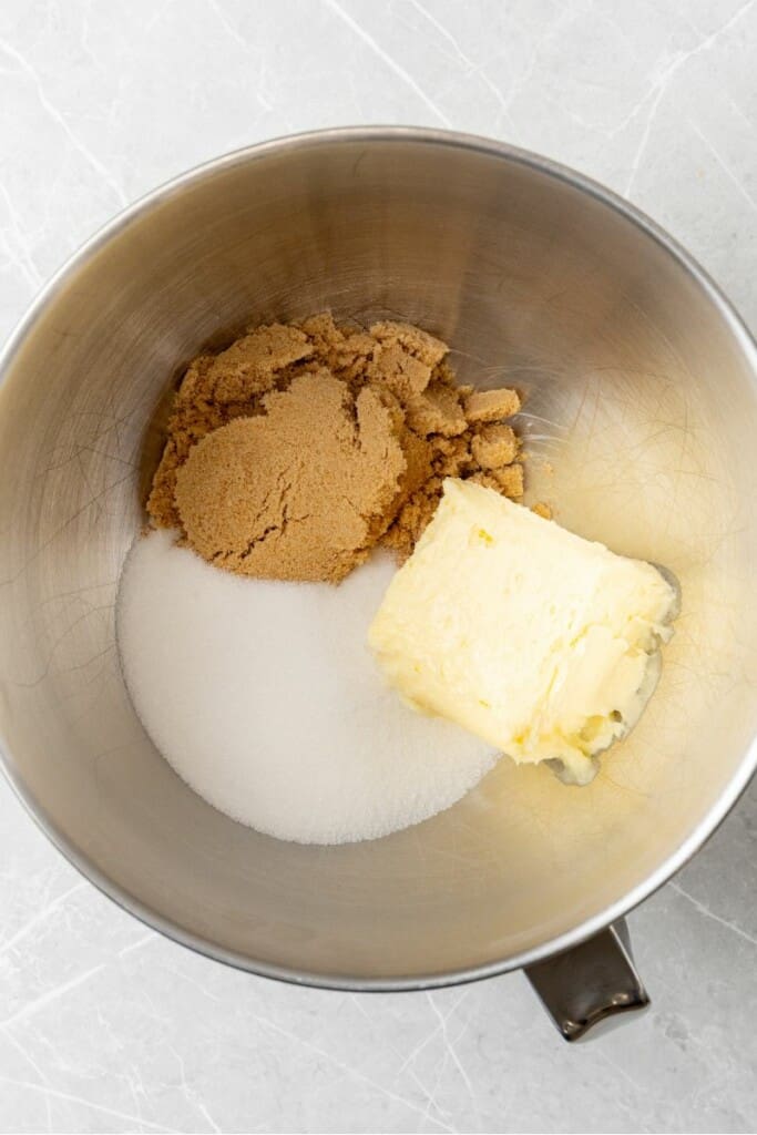 adding brown sugar, white sugar and butter to a mixing bowl