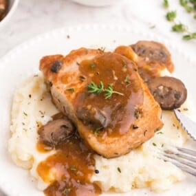 seared pork chop over creamy potatoes and mushroom gravy