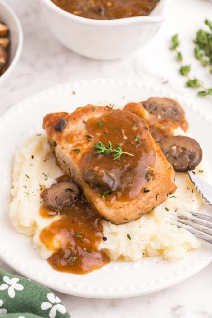 seared pork chop over creamy potatoes and mushroom gravy 