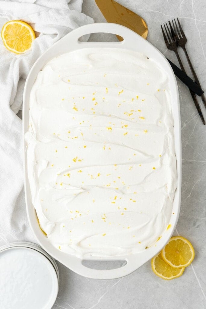 adding a layer of cool whip onto lemon pudding with lemon zest on top  