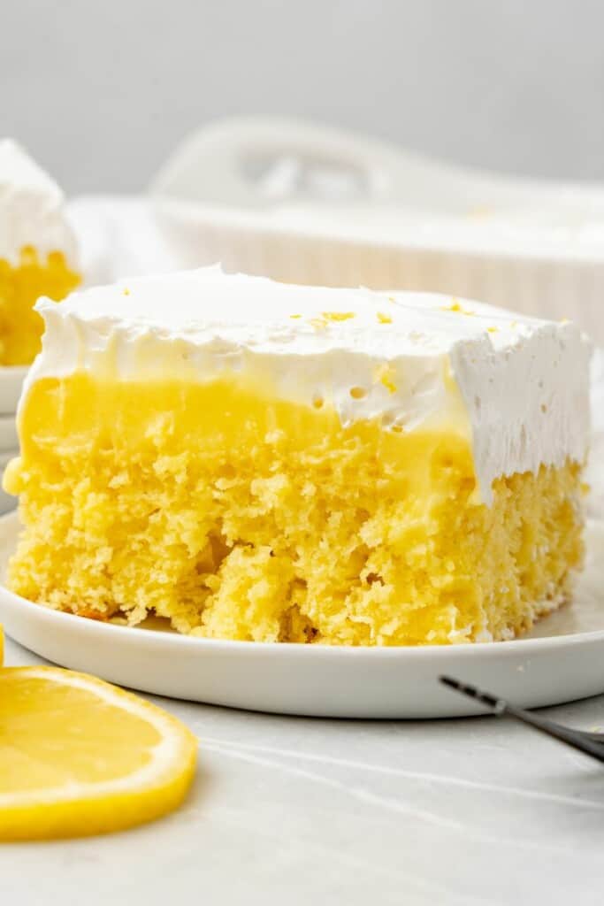 a slice of lemon poke cake on a white plate 