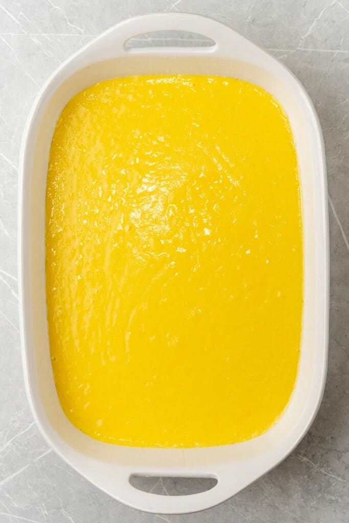 adding lemon cake batter to a baking pan 