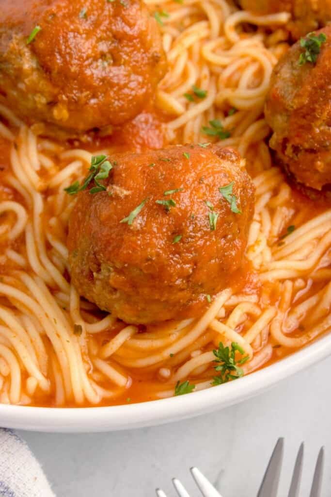 close up shot of beef meatballs over spaghetti marinara 