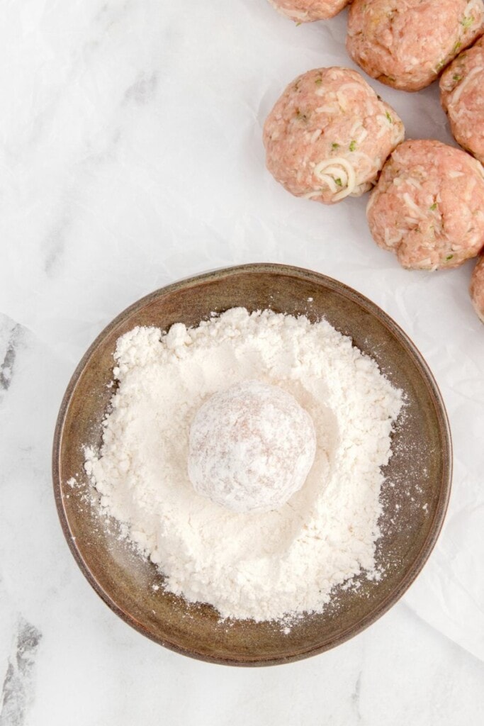 lightly coating meatballs with flour 