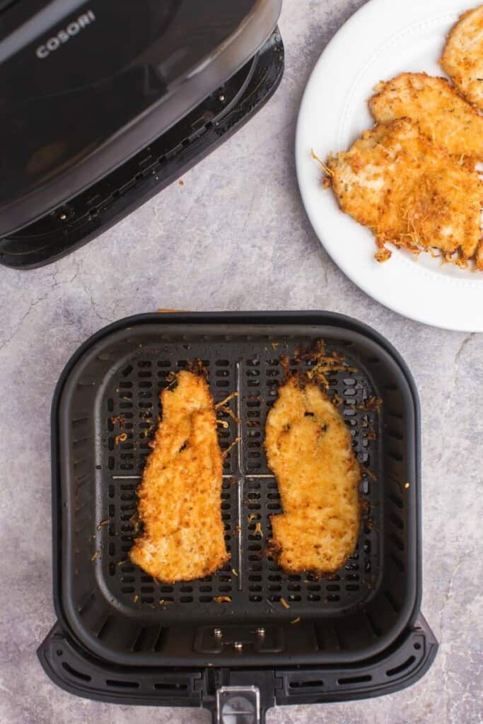 cooked parmesan crusted chicken in an air fryer basket 