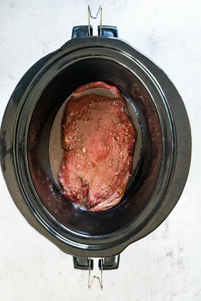 adding raw marinated steak to crockpot