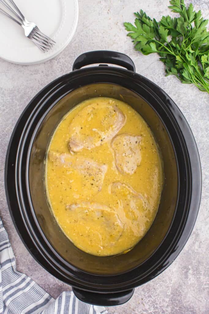 Thin pork chops cooking in slow cooker.