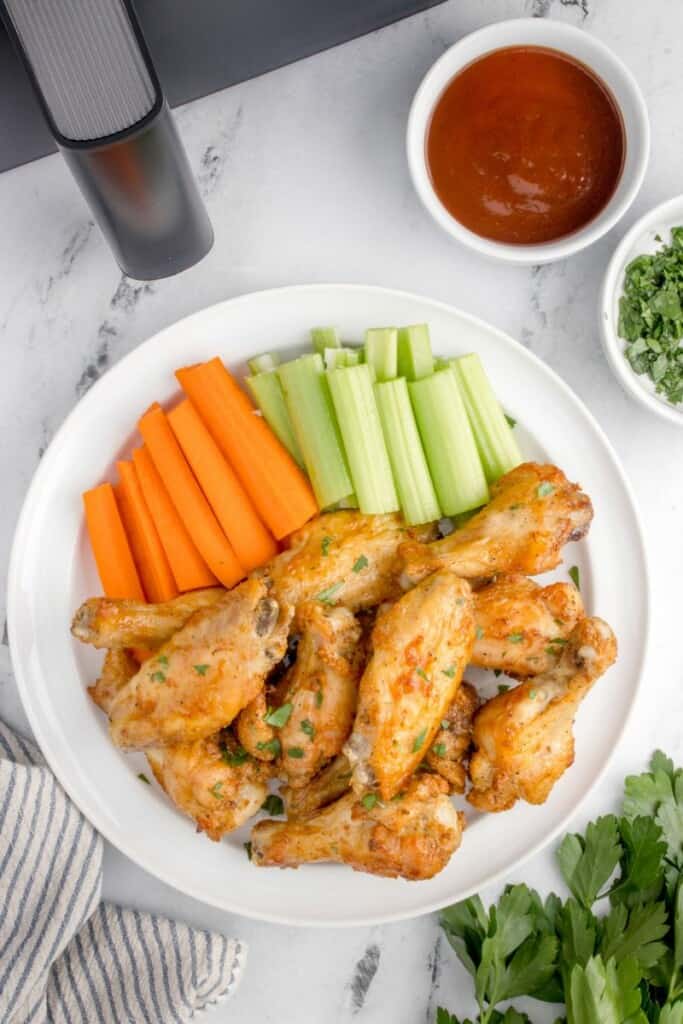 air fryer chicken wings with baking powder on a plate with cut veggies 