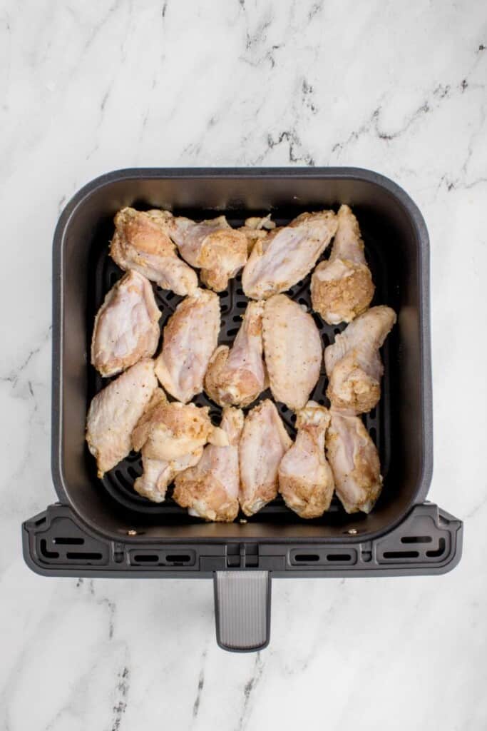 adding seasoned raw chicken wings to air fryer basket 