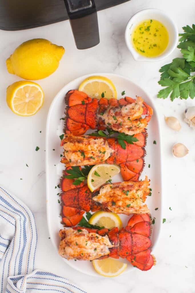 Air fried lobster tails lined up on a platter with garnish.