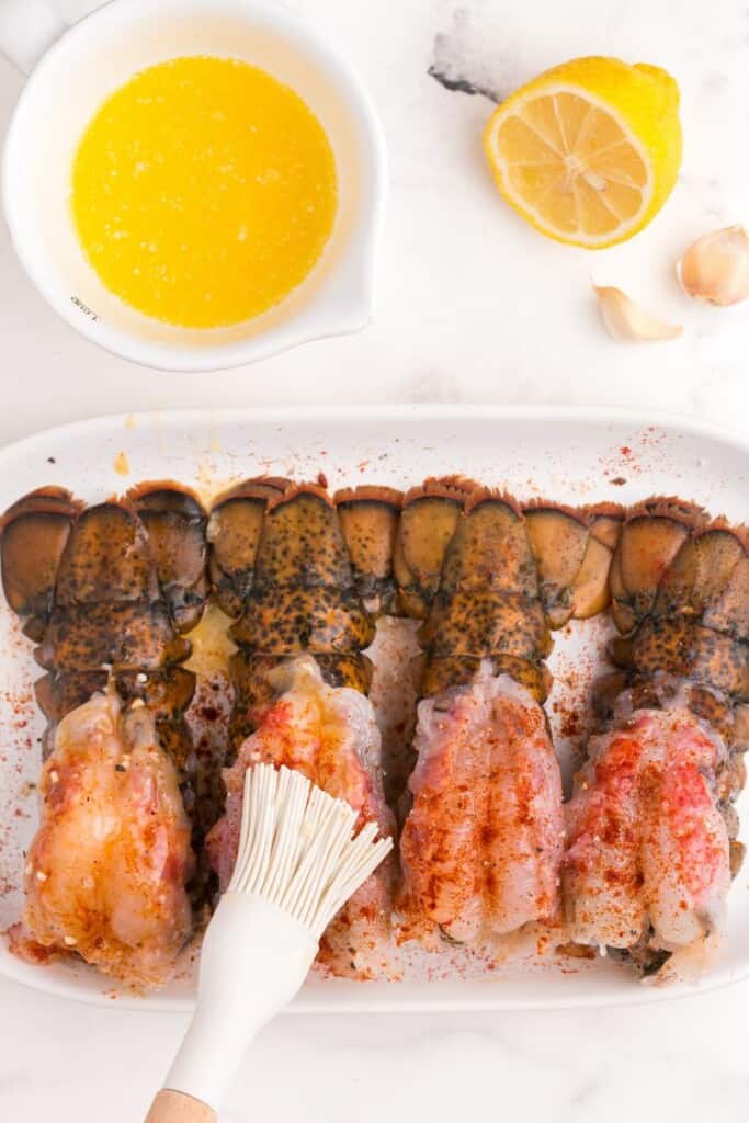 Brushing lobster with lemon garlic butter sauce.