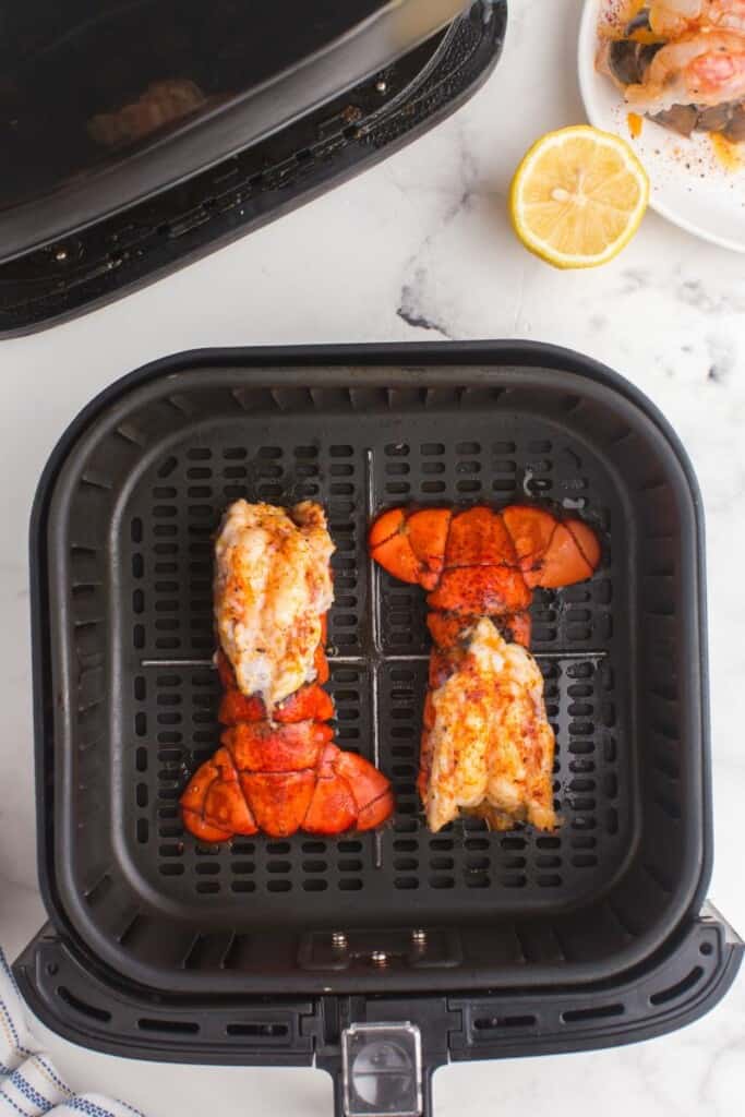 Lobster tails in air fryer basket.