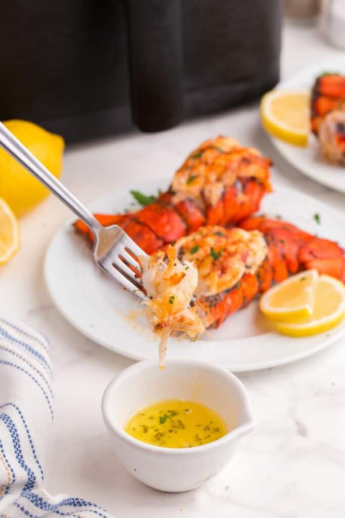 Dipping lobster meat into lemon garlic butter.