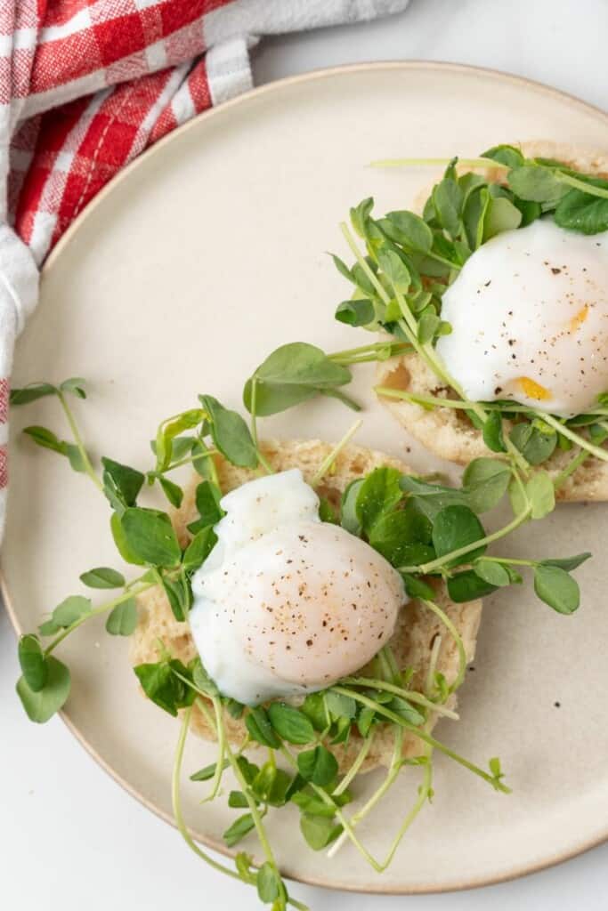 English muffins topped with arugula and a poached egg, seasoned with salt and pepper.