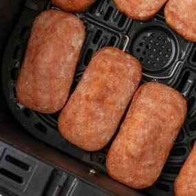 Close up of slices of spam in an air fryer.