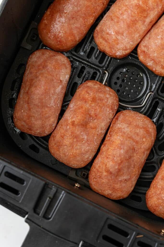 Close up of slices of spam in an air fryer.