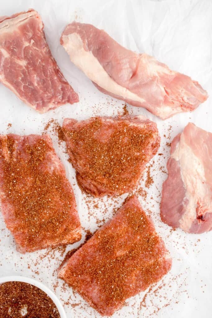 Seasoned and unseasoned spare rib cuts on parchment paper.