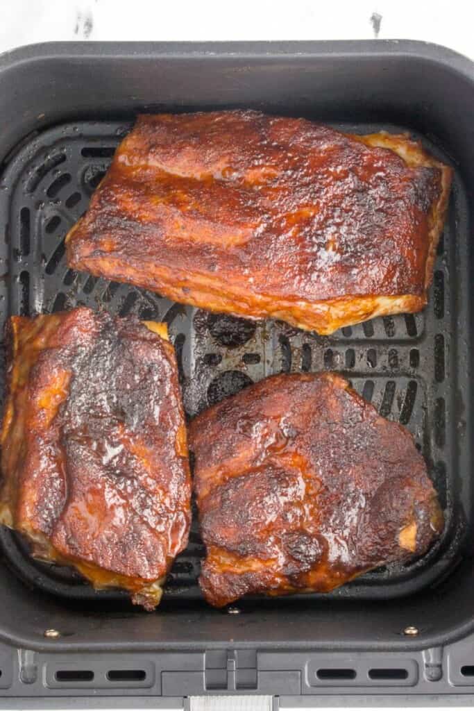Glazed pork ribs in air fryer basket.