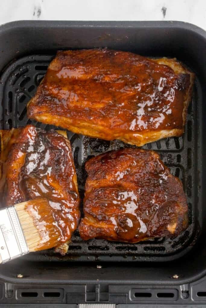 Brushing barbecue sauce onto spare ribs.