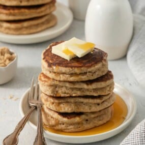4 brown sugar pancakes on a plate, covered with syrup.