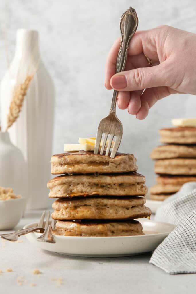 Fork cutting into a stack of brown sugar pancakes