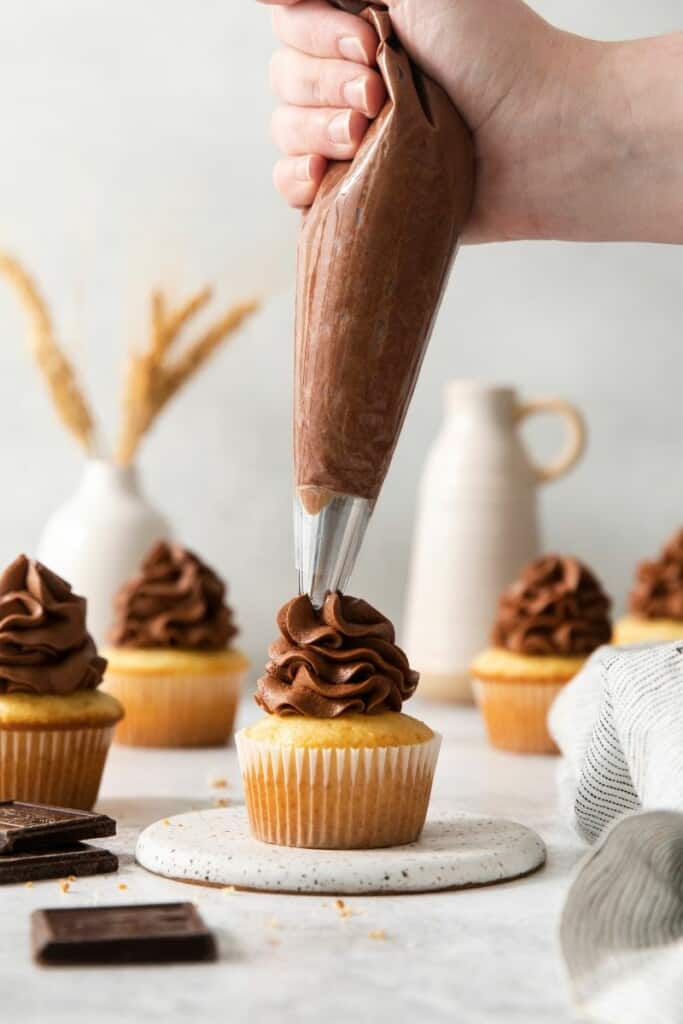 Frosting a vanilla cupcake.