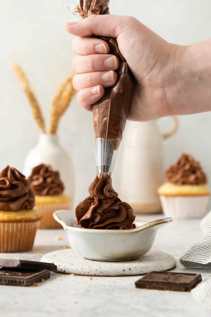Squeezing chocolate icing into a small dish.