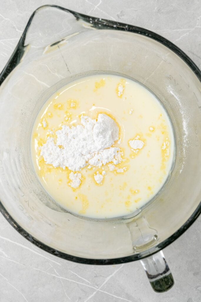 Vanilla pudding mix with powdered sugar and milk in a mixing bowl to make frosting.