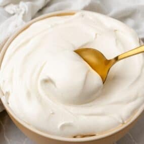 Cool whip frosting being scooped up with a gold spoon.