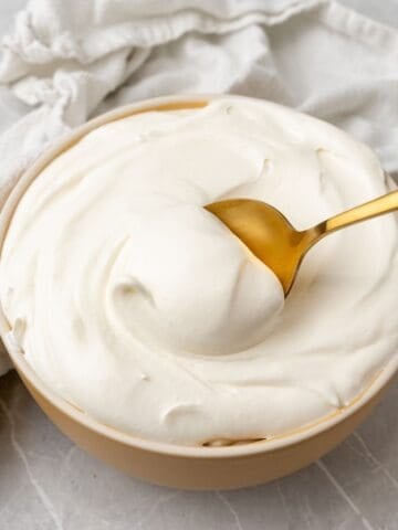 Cool whip frosting being scooped up with a gold spoon.