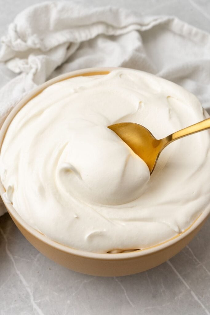 Cool whip frosting being scooped up with a gold spoon.