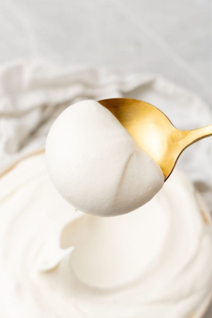 Close up of a gold spoon with a scoop of cool whip icing on it.
