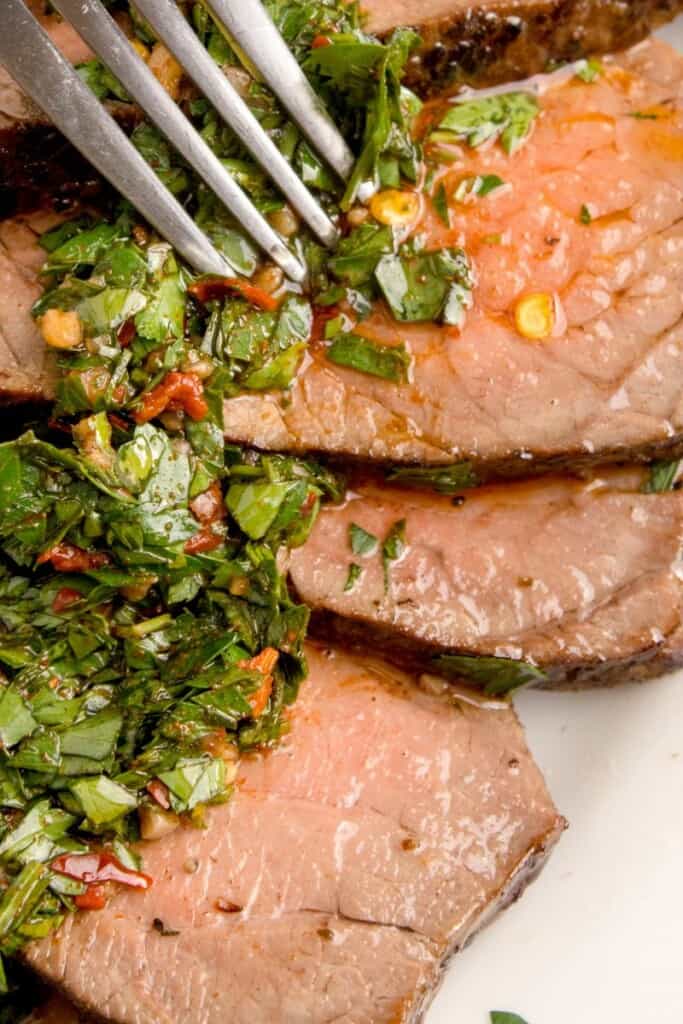 Close up of london broil with chimichurri.