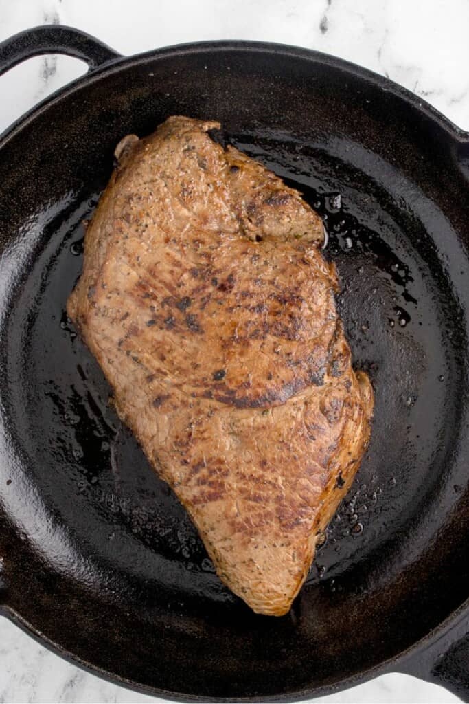 Searing meat in a cast iron skillet.