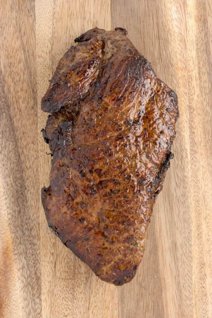 Baked London broil resting on a cutting board.