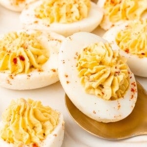 Very close up of the million dollar deviled eggs with a spoon picking one up.