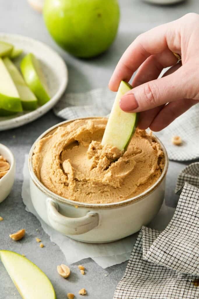 Scooping up some peanut butter yogurt dip on an apple slice.