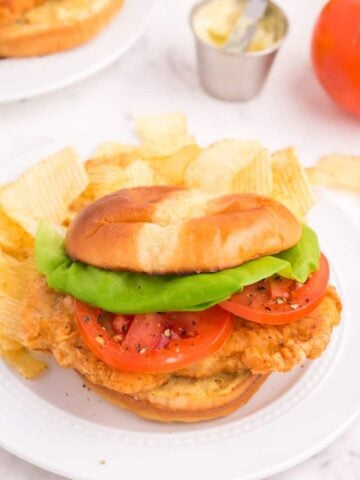 Fried pork chop sandwich with lettuce and tomato.