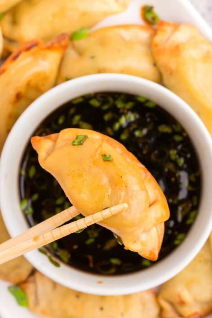 close up of fried dumpling over dipping sauce 
