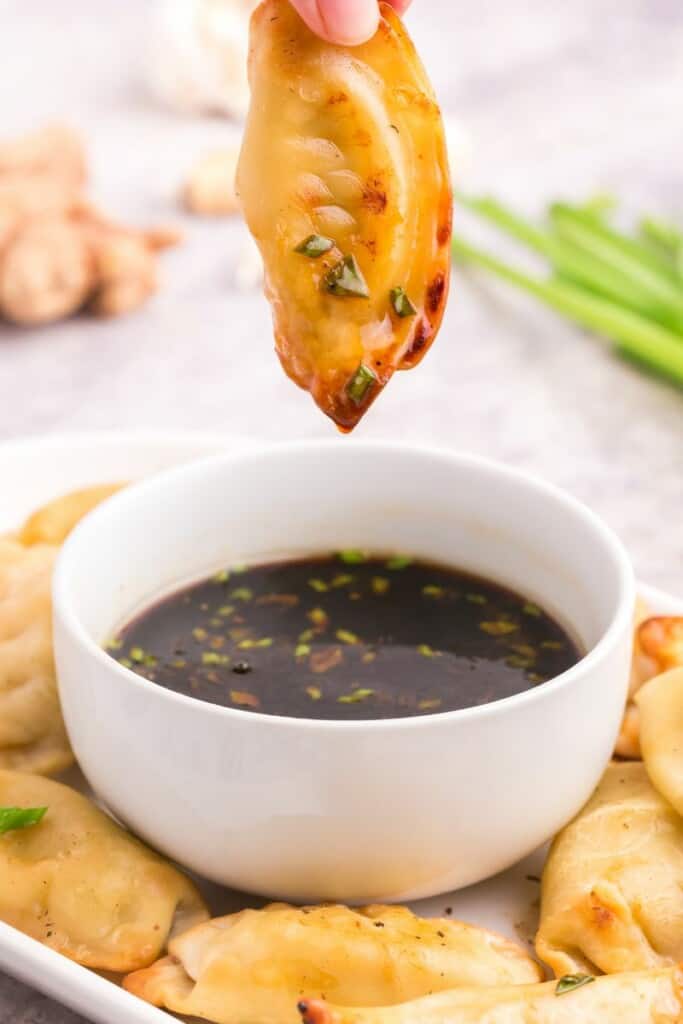 dipping fried potsticker into pot sticker dumpling sauce 