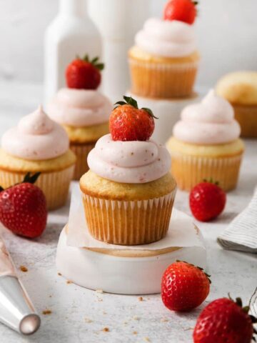 Vanilla cupcakes with homemade strawberry frosting and a fresh berry on top.