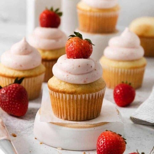 Vanilla cupcakes with homemade strawberry frosting and a fresh berry on top.