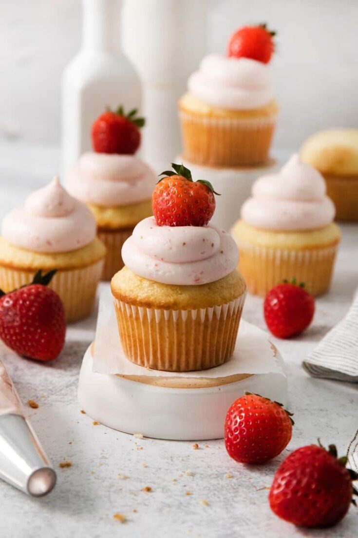 Vanilla cupcakes with homemade strawberry frosting and a fresh berry on top.