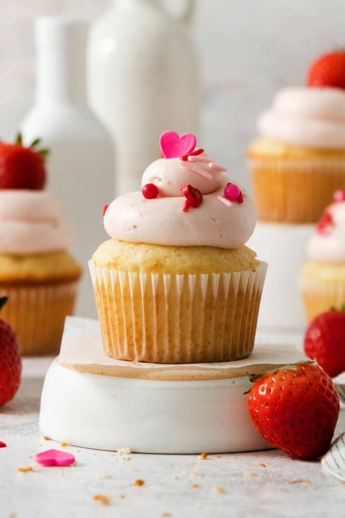 Close up of iced vanilla cupcake with homemade cream cheese frosting, decorated for valentines.