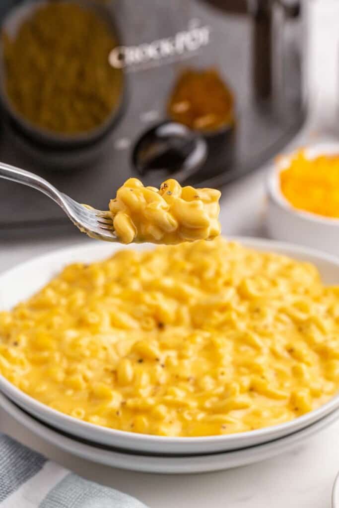 A bite of cheesy slow cooker macaroni lifted on a fork.