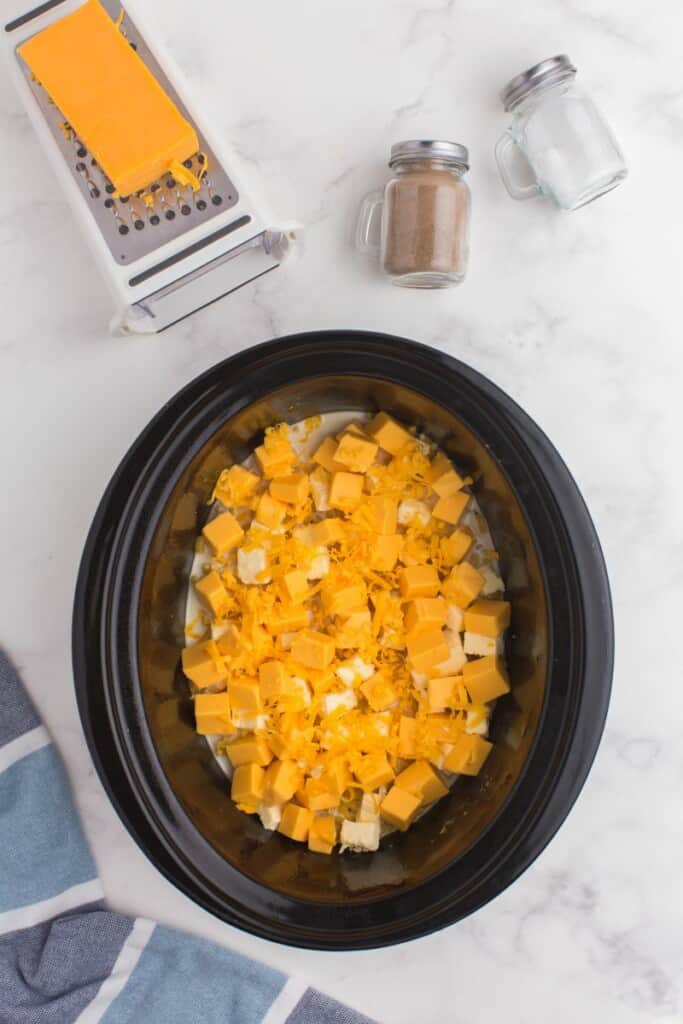 Cubed cheeses, butter, and milk in slow cooker.