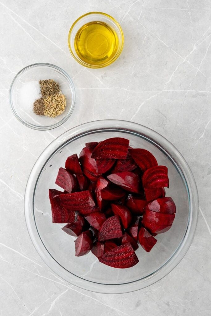 Ingredients needed to air fry beets: red beets, olive oil, dried rosemary, thyme, salt, and pepper.
